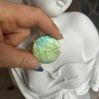 Pendentif en labradorite forme Ronde, style galette plate en provenance de Madagascar. dimension : 3.5 cm., épaisseur environ 3 mm. Cercle et bélière doré. Boutique Minéraux du Monde La Porte des Secrets