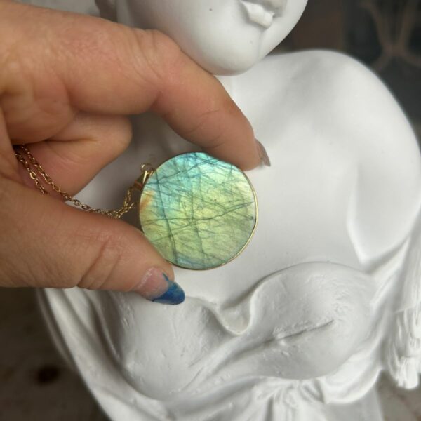 Pendentif en labradorite forme Ronde, style galette plate en provenance de Madagascar. dimension : 3.5 cm., épaisseur environ 3 mm. Cercle et bélière doré. Boutique Minéraux du Monde La Porte des Secrets