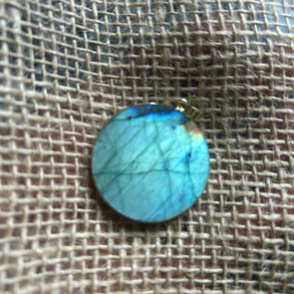 Pendentif en labradorite forme Ronde, style galette plate en provenance de Madagascar. dimension : 3.5 cm., épaisseur environ 3 mm. Cercle et bélière doré. Boutique Minéraux du Monde La Porte des Secrets