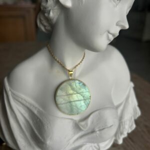 Pendentif en labradorite forme Ronde, style galette plate en provenance de Madagascar. dimension : 3.5 cm., épaisseur environ 3 mm. Cercle et bélière doré. Boutique Minéraux du Monde La Porte des Secrets